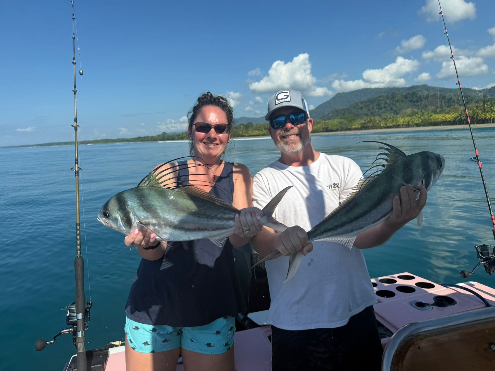 Two happy clients holding a large roosterfish