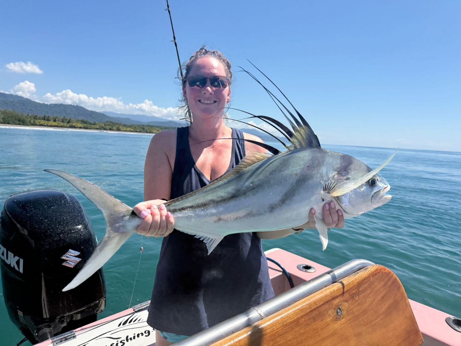 Adult woman smiling while holding a large roosterfish