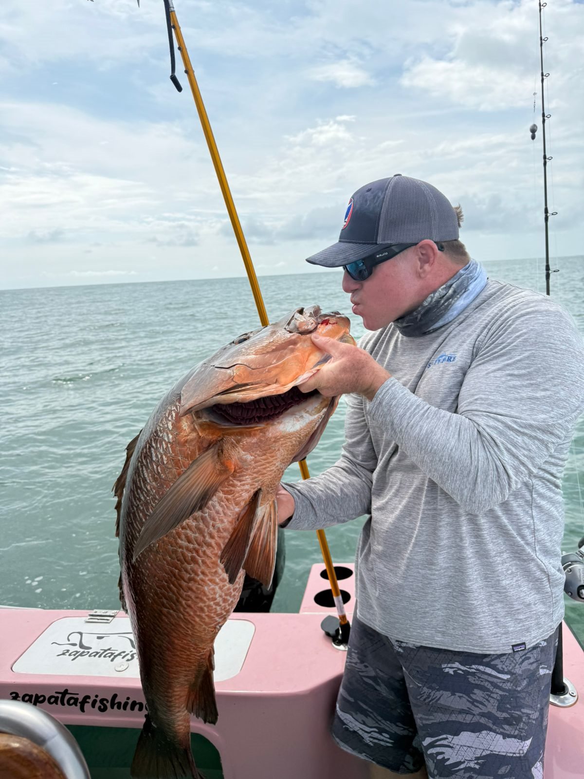 Adult angler lifting an exceptionally large grouper beside the boat