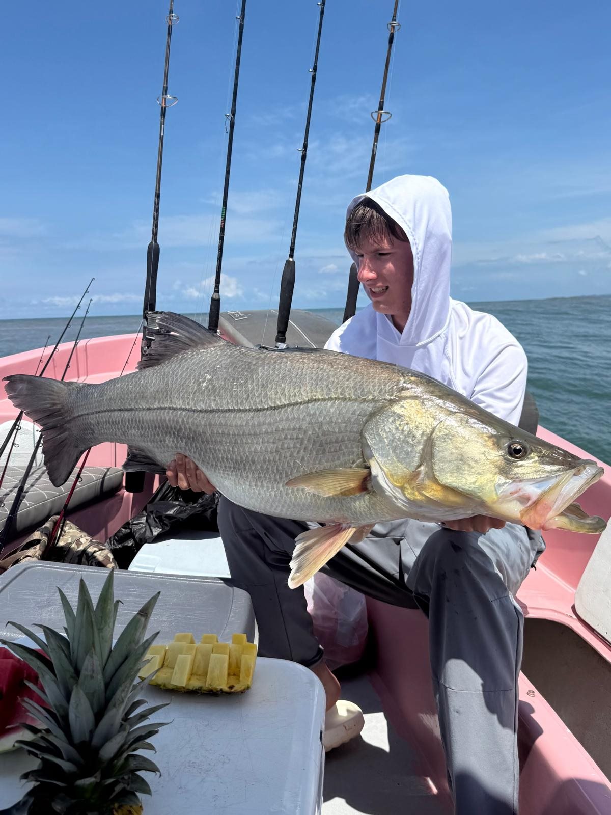 Young adult angler holding an exceptionally large snook aboard the pink boat